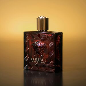 Close-up of Versace Eros Flame perfume bottle with a warm yellow backdrop.